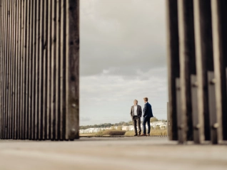 Two businessmen standing behind fencing