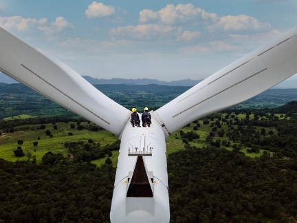 Two workers in the distance on a high level turbine
